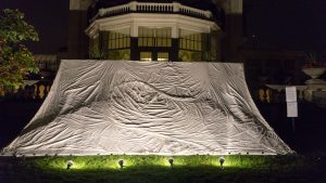 Made of natural cotton by artist Gloria Stein, River: The Shroud of Buczacz, was a 16 foot by 24 foot topographically accurate scale model of the site in Poland where 1500 Jews were murdered during the course of one night in early spring 1943. Stein’s father, then but a small child, managed to survive the massacre, but the poisoned river would feature in the nightmares of the Holocaust that would haunt him for the rest of his life. The shroud both concealed and revealed as it reminded the viewer of the story’s saddest relic, that “many parts of our precious earth are still being poisoned with the blood of innocent victims”.